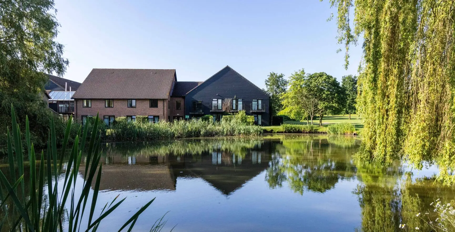 Exterior view of Champneys Springs across the lake, surrounded by countryside